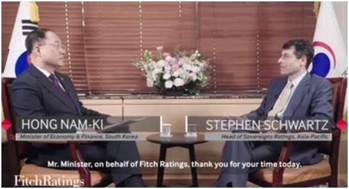 Hong Nam-ki (left), the minister of economy and finance, holds an interview with global credit appraiser Fitch Ratings in this still from a video posted on its website.