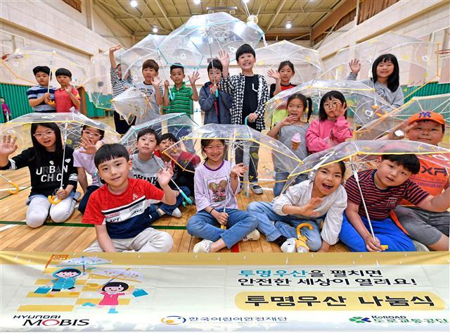 서울 고산초등학교 학생들이 현대모비스가 배포한 투명 우산을 들고 포즈를 취하고 있다.