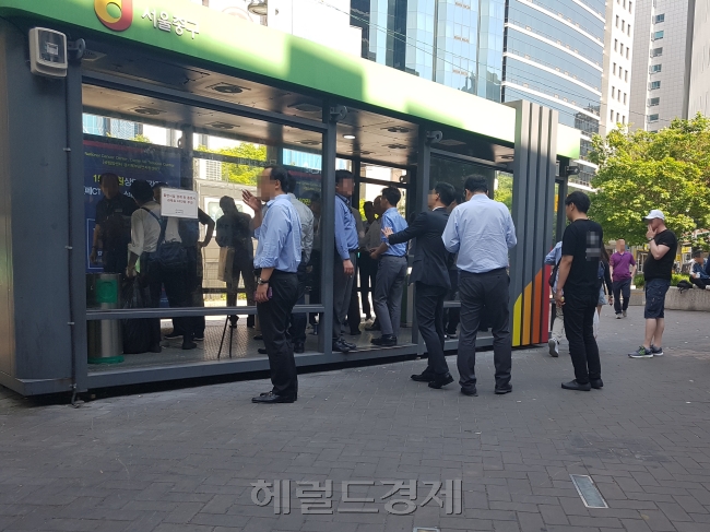 지난 23일 서울 명동 인근 흡연부스. 시민들과 외국인 관광객들이 흡연부스 내부가 아닌 흡연부스 주변에서 흡연을 하고 있다.  최원혁 기자/choigo@heraldcorp.com