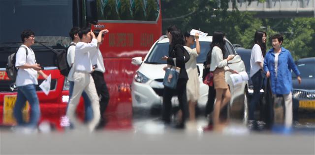 24일 서울에 올해 첫 폭염주의보가 발효되는 등 주말까지 전국이 한여름 날씨를 보일 것으로 예보됐다. 사진은 23일 서울 세종대로에서 시민들이 지열이 피어오르는 횡단보도 위를 지나고 있는 모습.  [연합]