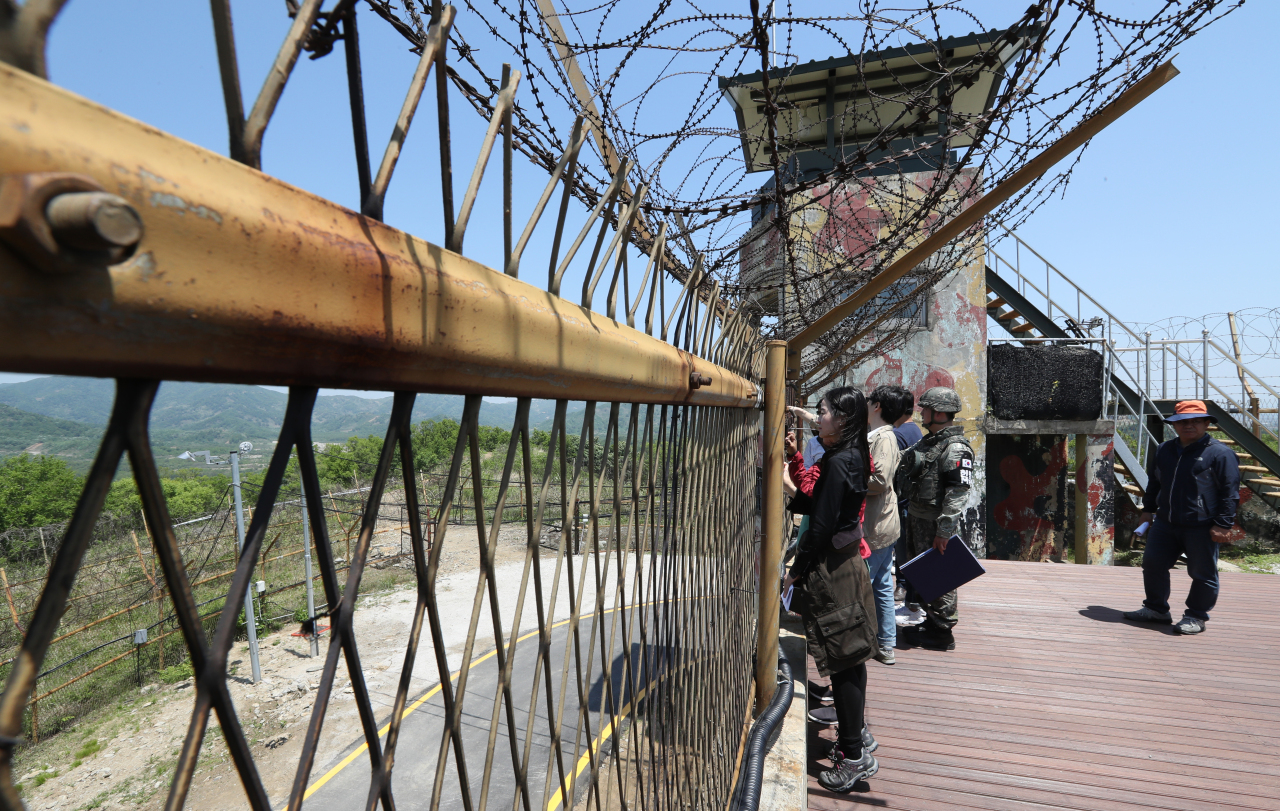 Visitors look through barbed fences near the Demilitarized Zone in Cheorwon County, Gangwon Province, on one of the three DMZ Peace Trails planned by the South Korean government. (Joint Press Corps)