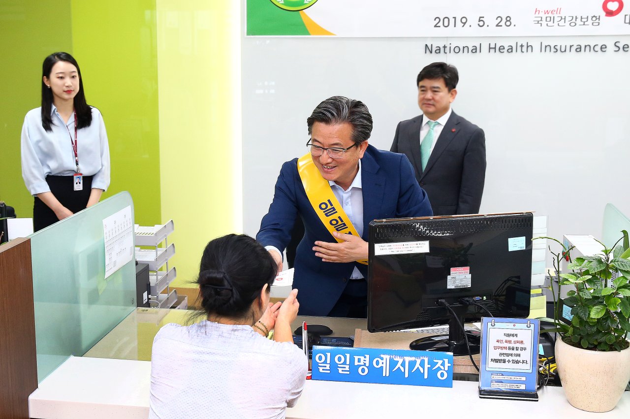 28일 오전 일일 명예지사장으로 위촉된 정용래 유성구청장이 민원인에게 건강보험증을 발급해 건네주고 있다.