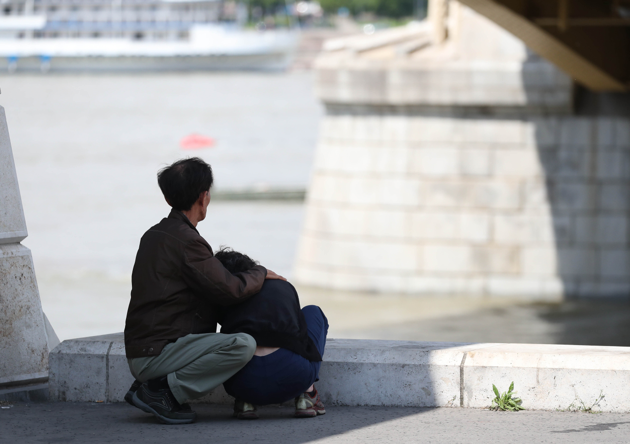 A berated family looks at the Danube river. Yonhap