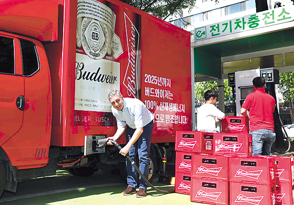 고동우 오비맥주 대표(왼쪽)가 전기차충전소에서 버드와이저 맥주를 운반하는 친환경 전기트럭을 충전하고 있다. [오비맥주 제공]