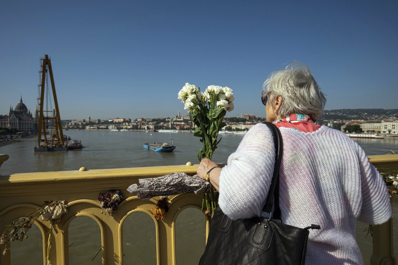 A woman holds a bunch of flowers Margaret Bridge, the scene of the deadly boat accident in Budapest, Hungary, Saturday, June 8, 2019. A sightseeing boat carrying 33 South Korean tourists was crashed by a large river cruise ship and sank in the River Danube on May 29. The body of seven tourists on board were retrieved on that night, seven tourists survived, 21 persons, including the two Hungarian crews went missing. Twelve more victims have been found and identified since then. (AP-Yonhap)