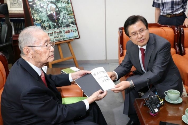 자유한국당 황교안 대표(오른쪽)가 10일 오후 서울 용산 전쟁기념관 군사 편찬연구 자문위원장실에서 6·25전쟁 영웅으로 불리는 백선엽 장군(예비역 대장)을 예방, 백 장군의 저서 '징비록'을 선물받고 있다. [연합뉴스]