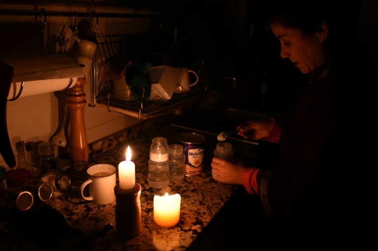 A woman prepares milk bottles by candle lights at her home in Montevideo during a massive power failure. (AFP)