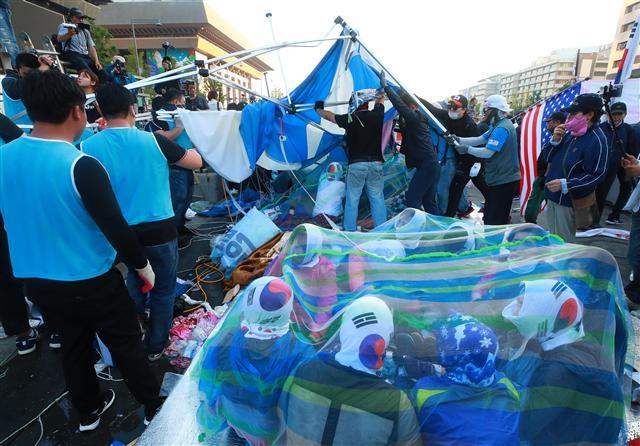 <YONHAP PHOTO-2147> 저항 속 광화문 대한애국당 천막 철거 (서울=연합뉴스) 홍해인 기자 = 25일 오전 서울 종로구 광화문 광장에서 농성 중이던 대한애국당(우리공화당) 천막을 서울시와 용역업체 관계자들이 당원들의 저항 속에 철거하고 있다. 서울시는 오전 5시 20분부터 천막 2동 등 불법 설치물에 대한 행정대집행을 실시 중이다. 대한애국당은 24일 당명을 '우리공화당'으로 개정했다. 2019.6.25 hihong@yna.co.kr/2019-06-25 07:38:34/ <저작권자 ⓒ 1980-2019 ㈜연합뉴스. 무단 전재 재배포 금지.>