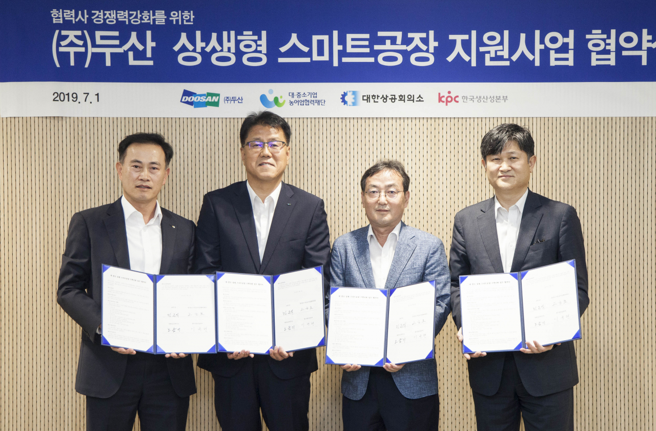 1일 서울 동대문 두산타워에서 열린 '㈜두산 상생형 스마트공장 지원사업' 협약식 참석자들이 협약서를 들고 기념촬영을 하고 있다. 왼쪽부터 노금기 대한상공회의소 상무, 민은식 ㈜두산 커뮤니케이션 상무, 고근모 대중소기업농어업협력재단 본부장, 이규현 한국생산성본부 본부장.[두산 제공]