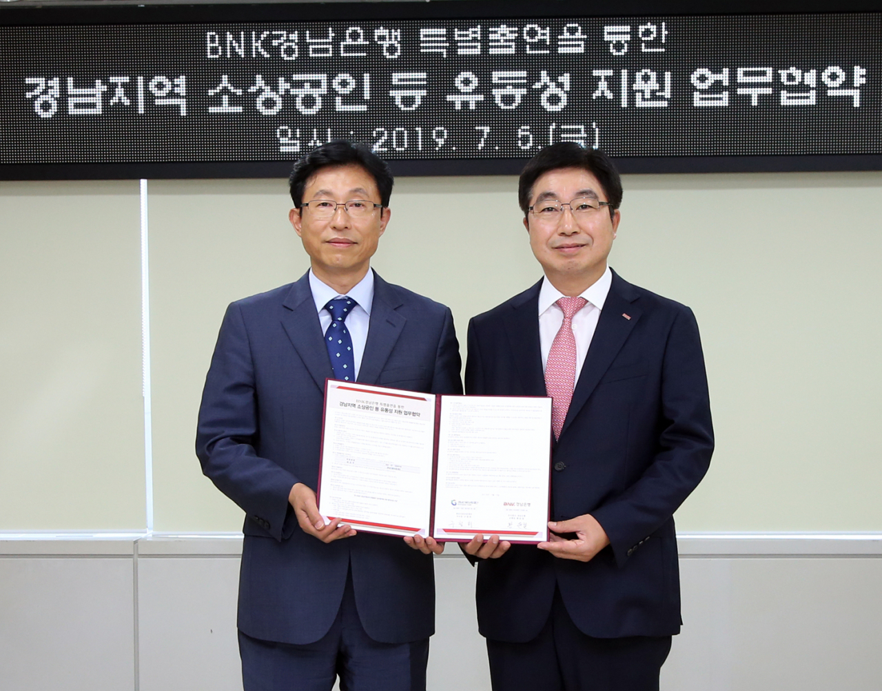 BNK경남은행 황윤철 은행장(사진 오른쪽)이 경남신용보증재단 구철회 이사장과 경남지역 소상공인 등 유동성 지원 업무 협약을 체결한 뒤 기념촬영하고 있다.