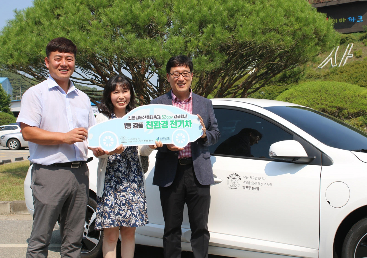 강용 친환경농산물자조금 관리위원장(오른쪽)이 '유기데이 경품 이벤트' 1등 당첨자에게 전기자동차와 증서를 전달하면서 기념촬영을 하고 있다. [친환경농산물의무자조금관리위원회 제공]