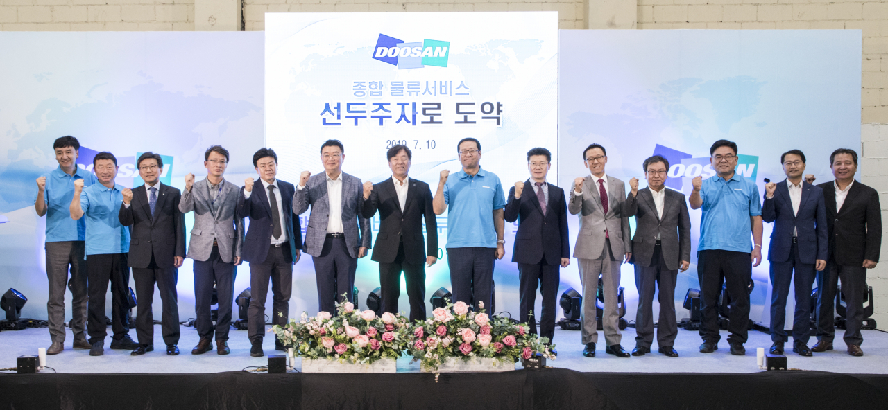 지난 10일 ㈜두산 산업차량 인천공장에서 열린 ‘종합 물류서비스 선두주자 도약’ 선포식에서 동현수 ㈜두산 부회장(왼쪽에서 일곱 번째), 곽상철 산업차량BG장(왼쪽에서 여섯 번째), 김환성 두산로지스틱스솔루션 대표(왼쪽에서 여덟 번째)를 비롯한 임직원과 고객들이 기념촬영을 하고 있다.[두산 제공]
