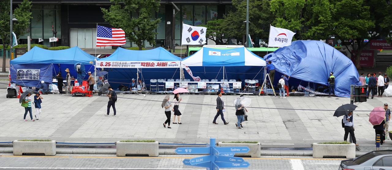 지난 10일 오후 서울 종로구 광화문광장에서 우리공화당 관계자들이 천막에 방수포를 설치하고 있다. 서울시는 이미 지난 8일 우리공화당 측에 “같은 날 오후 6시까지 자진 철거하라”며 2차 계고장을 보냈다. [연합]