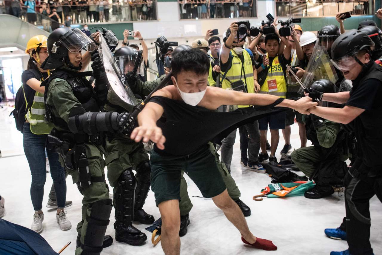 Police officers tear the shirt of a protester during a clash inside a shopping arcade in Sha Tin of Hong Kong after a rally against a controversial extradition law proposal in Sha Tin district of Hong Kong on July 14, 2019.(AFP)