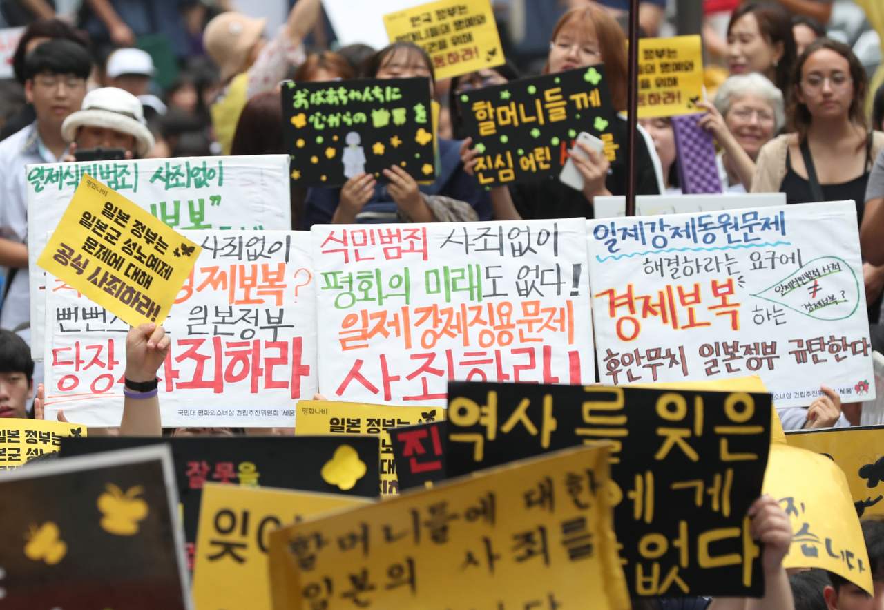 17일 서울 종로구 옛 일본대사관 앞에서 열린 제1396차 일본군 성노예제 문제 해결을 위한 정기 수요집회에서 참가자들이 역사 사죄 촉구 및 경제 보복을 규탄하는 피켓을 들고 구호를 외치고 있다. 연합뉴스