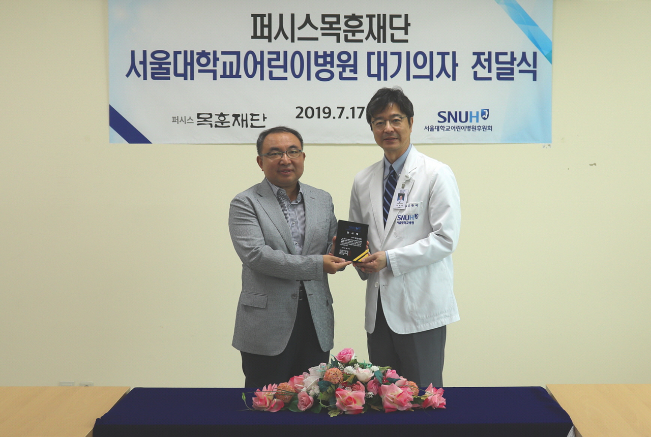 퍼시스 목훈재단 이상배 부사장(왼쪽)과 김한석 서울대학교어린이병원장이 지난 17일 진료대기의자 270세트 전달식에서 사진촬영을 하고 있다.