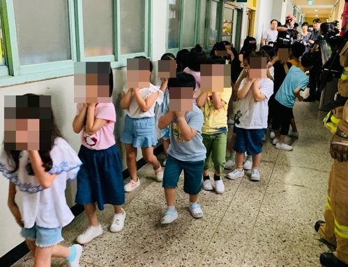25일 서울 구로구의 한 초등학교에서 학생들이 코와 입을 가린 채 건물 밖으로 대피하고 있다. [구로소방서 제공]