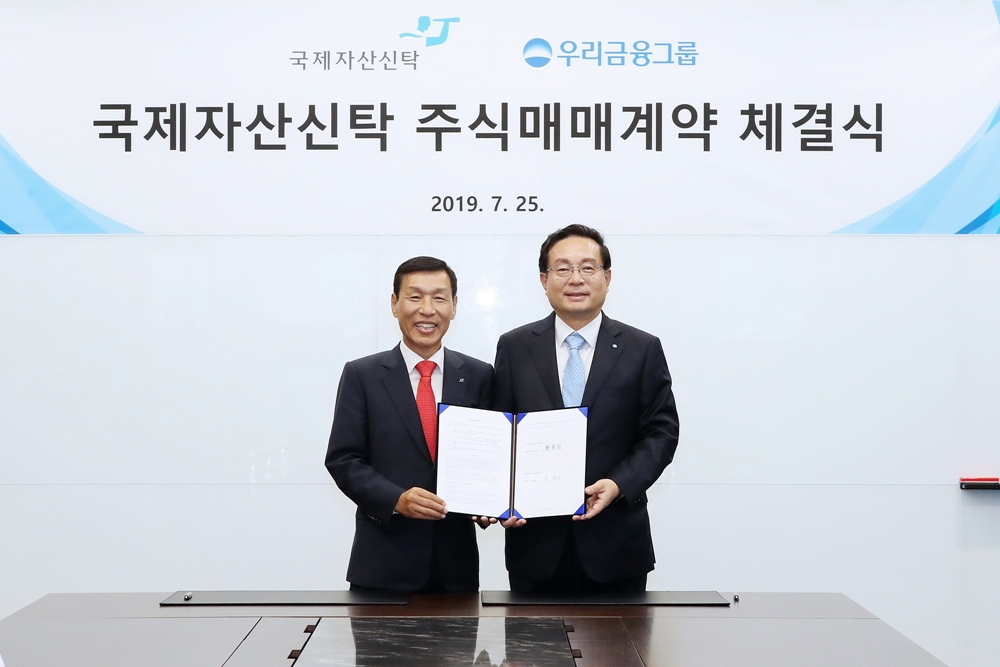25일 서울 종로구 법무법인 세종에서 손태승 우리금융그룹 회장(오른쪽)과 유재은 국제자산신탁 회장이 국제자산신탁 경영권 지분 인수를 위한 주식매매계약(SPA)을 체결한 뒤 기념촬영을 하고 있다. [우리금융 제공]