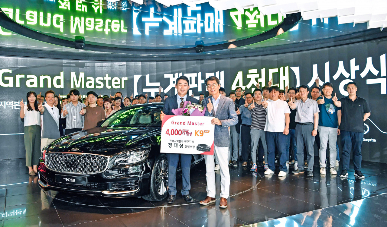 누계판매 4000대를 달성한 ‘그랜드 마스터’ 정태삼 영업부장(왼쪽)이 권혁호 기아차 국내영업본부장과 기념촬영을 하고 있다. [기아자동차 제공]