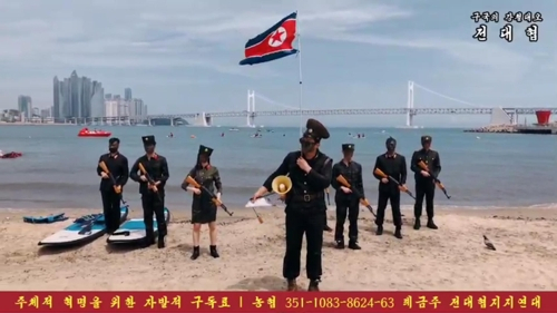 26일 전대협 회원 8명이 광안리 해변에서 북한군 퍼포먼스에 나선 모습. 모의 총기 등을 손에 들고 있는 모습과 인공기가 눈에 띈다. [SNS 캡처]