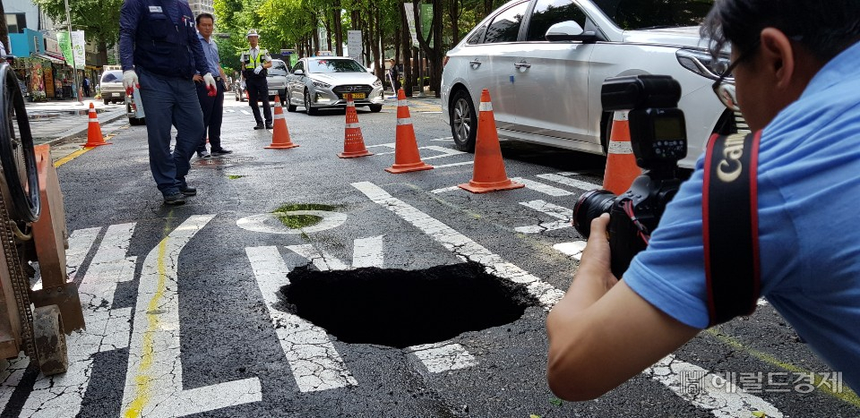 1일 내린 비로 청계천 1가 효령빌딩 앞에 약 1m 크기로 생긴 싱크홀을 사진 기자들이 촬영을 하고 있다. 중구는 하얀 포장으로 덮어 차량이 다니지 못하도록 임시 조치를 취했다. 정희조 기자/checho@heraldcorp.com