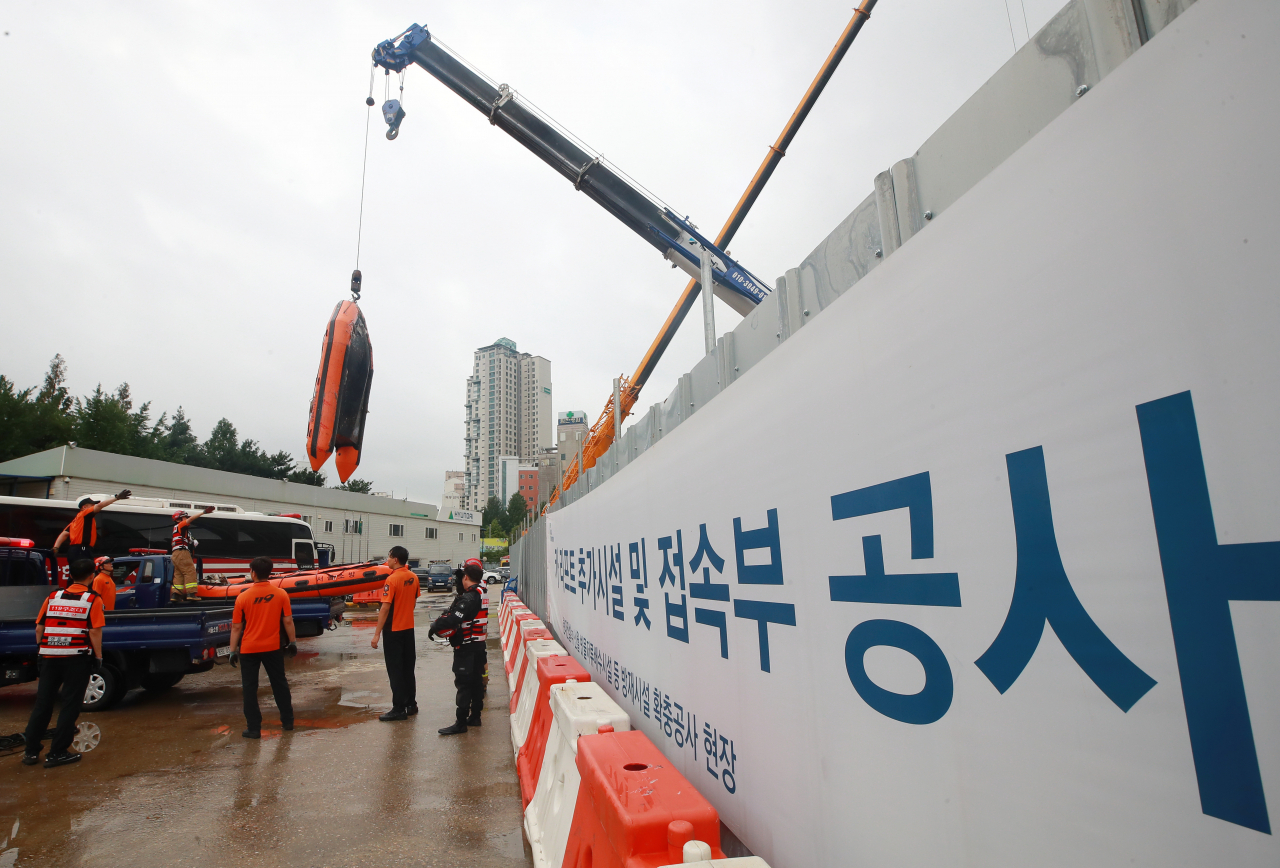1일 오전 서울 양천구 목동 빗물 배수시설 공사 현장 수몰지에서 실종자 수색과 시신 수습을 마친 119 구조대원들이 크레인을 이용해 지상으로 고무 보트를 옮기고 있다. 소방당국과 양천구청은 이날 오전 5시 42분과 47분에 배수시설에서 시신 2구를 발견했으며, 이들은 실종됐던 시공사 직원 안모씨와 미얀마 국적 협력업체 직원으로 확인됐다고 밝혔다. 연합뉴스