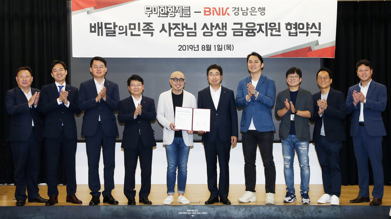 BNK경남은행 황윤철 은행장(사진 오른쪽에서 다섯번째)과 ㈜우아한형제들 김봉진 대표가 ‘배달의민족 사장님 상생 금융지원 협약’을 체결하고 있다.