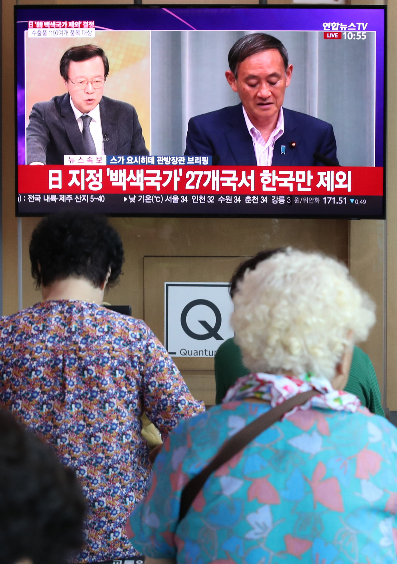 일본 정부가 각의(국무회의)에서 전략물자 수출 간소화 대상인 백색국가 명단(화이트 리스트)에서 한국을 제외하는 수출무역관리령 개정안을 결정한 2일 오전 서울역에서 시민들이 스가 요시히데 관방장관의 브리핑 화면을 보고 있다. ［연합］