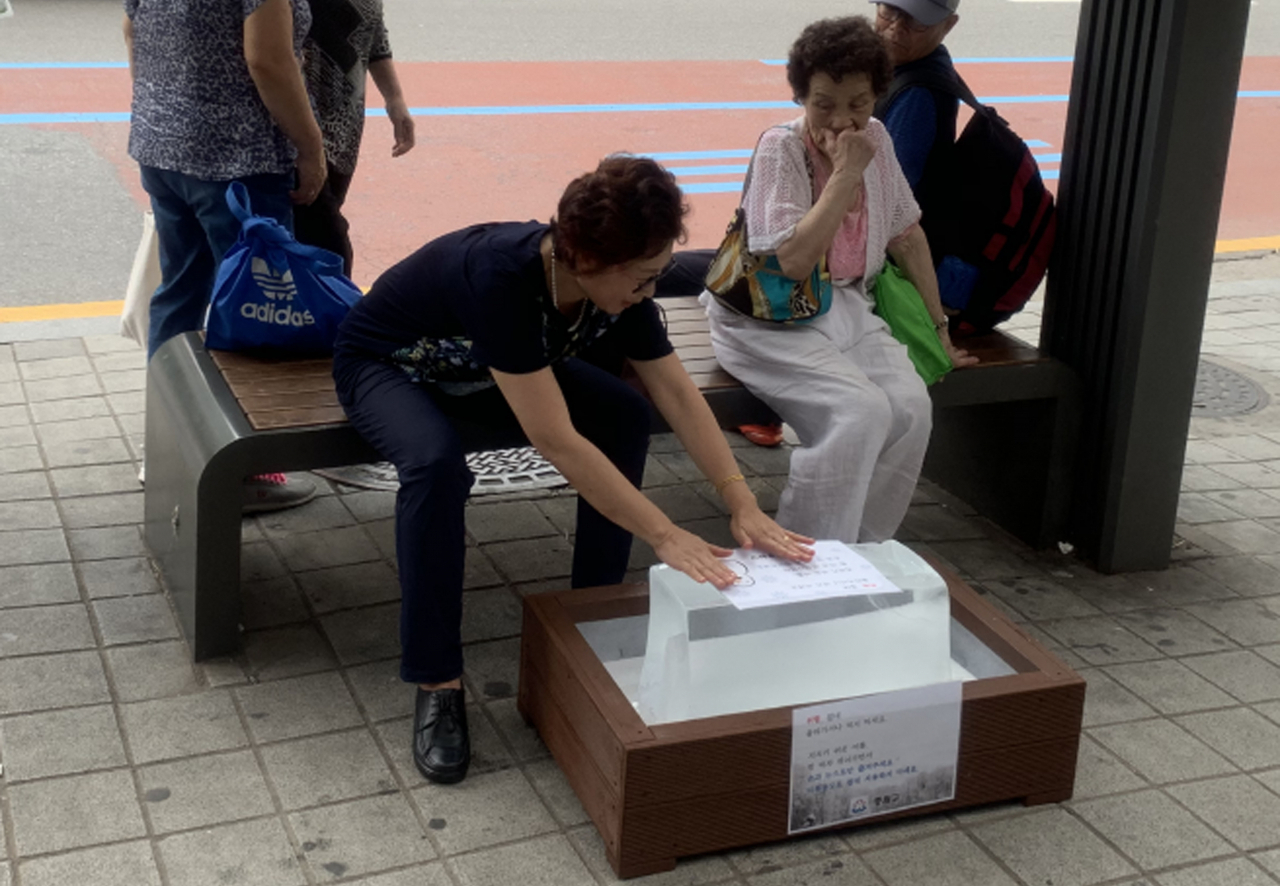 성남시 모란역 버스정류장에 비치한 얼음에 시민이 더위를 식히고있다.[성남시 제공]