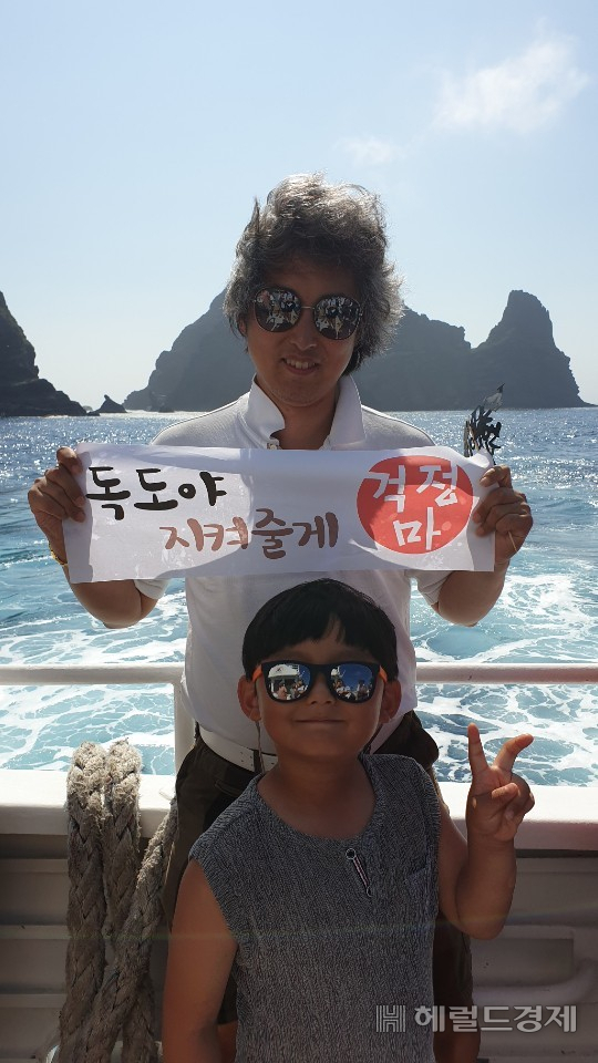 배기표 경제평론가가 아들과 함께 독도에 가 독도야 지켜줄게 걱정마라는 플랭카드를 들고 사진을 찍고 있다.