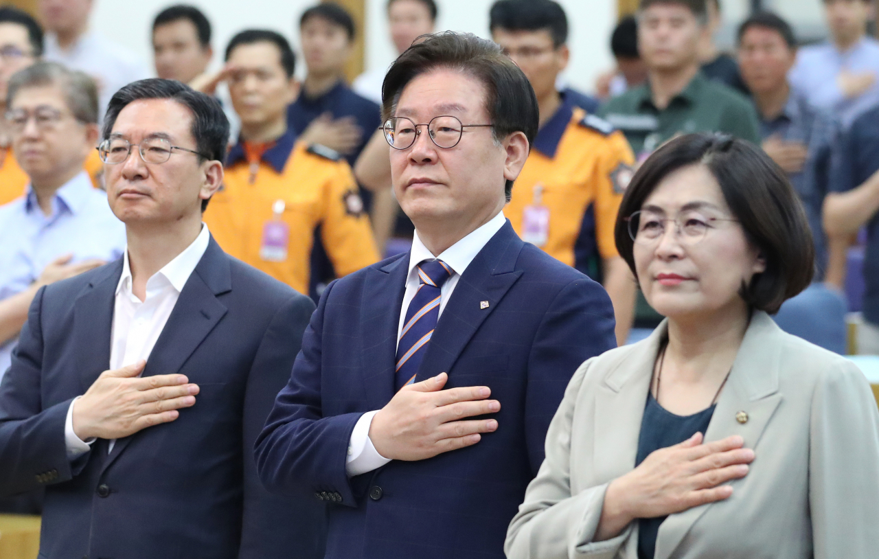 이재명 경기도지사(가운데)와 더불어민주당 정성호(왼쪽), 유승희 의원이 지난달 29일 오전 국회 의원회관에서 열린 '건물 내 재난시 구조요청 비상전원 확보 의무화 토론회'에 참석해 국기에 경례하고 있다. 연합뉴스