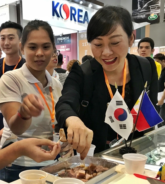‘필리핀식품박람회(WOFEX 2019)’를 찾은 현지인들이 대표적인 야식인 소주+족발 세트를 맛보고 있다. [aT 제공]