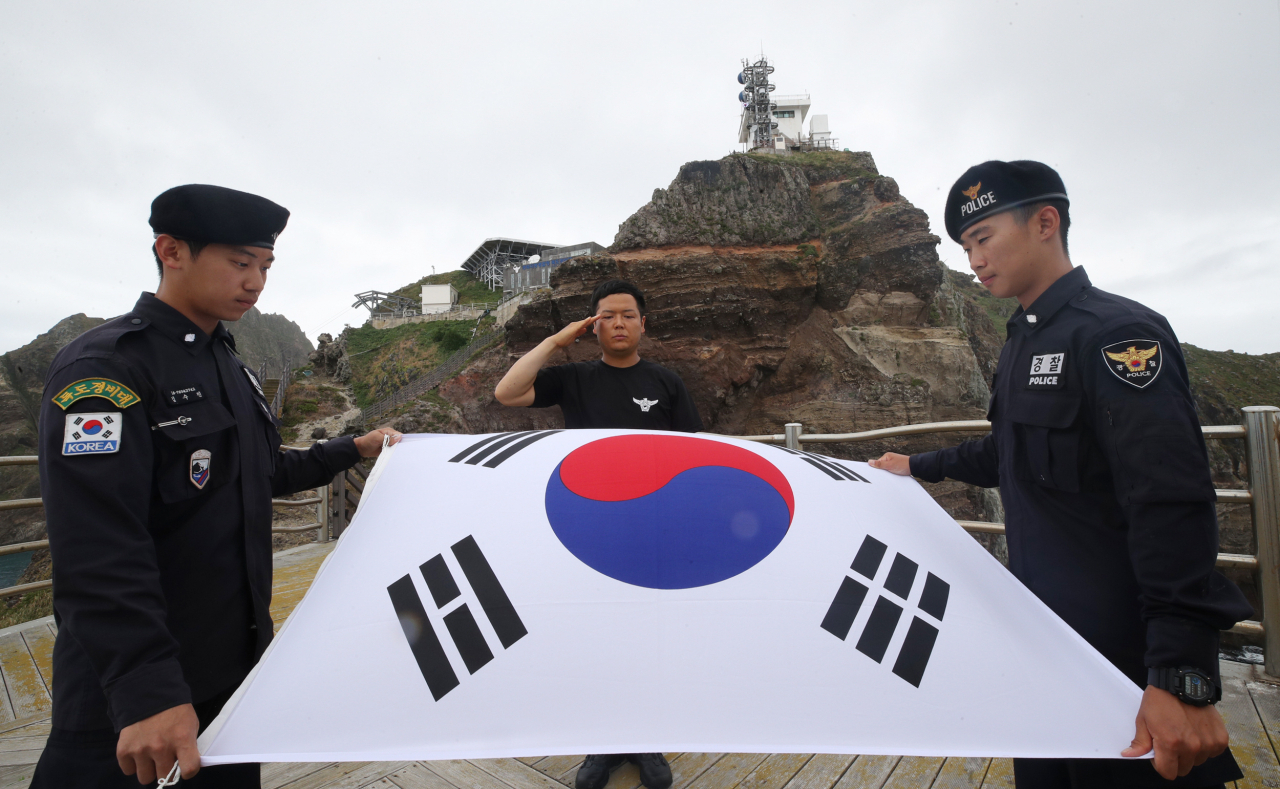 독도에서 독도경비대원들이 태풍 비바람으로 훼손된 태극기를 내리고 새 태극기를 게양하고 있다.[연합]