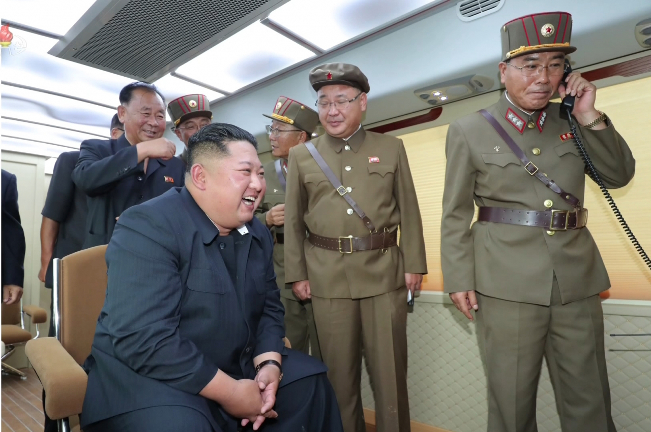 김정은 북한 국무위원장이 지난 16일 '새 무기' 시험사격을 지도하면서 수행원들과 지휘소 모니터 앞에서 환하게 웃고 있다. [연합]