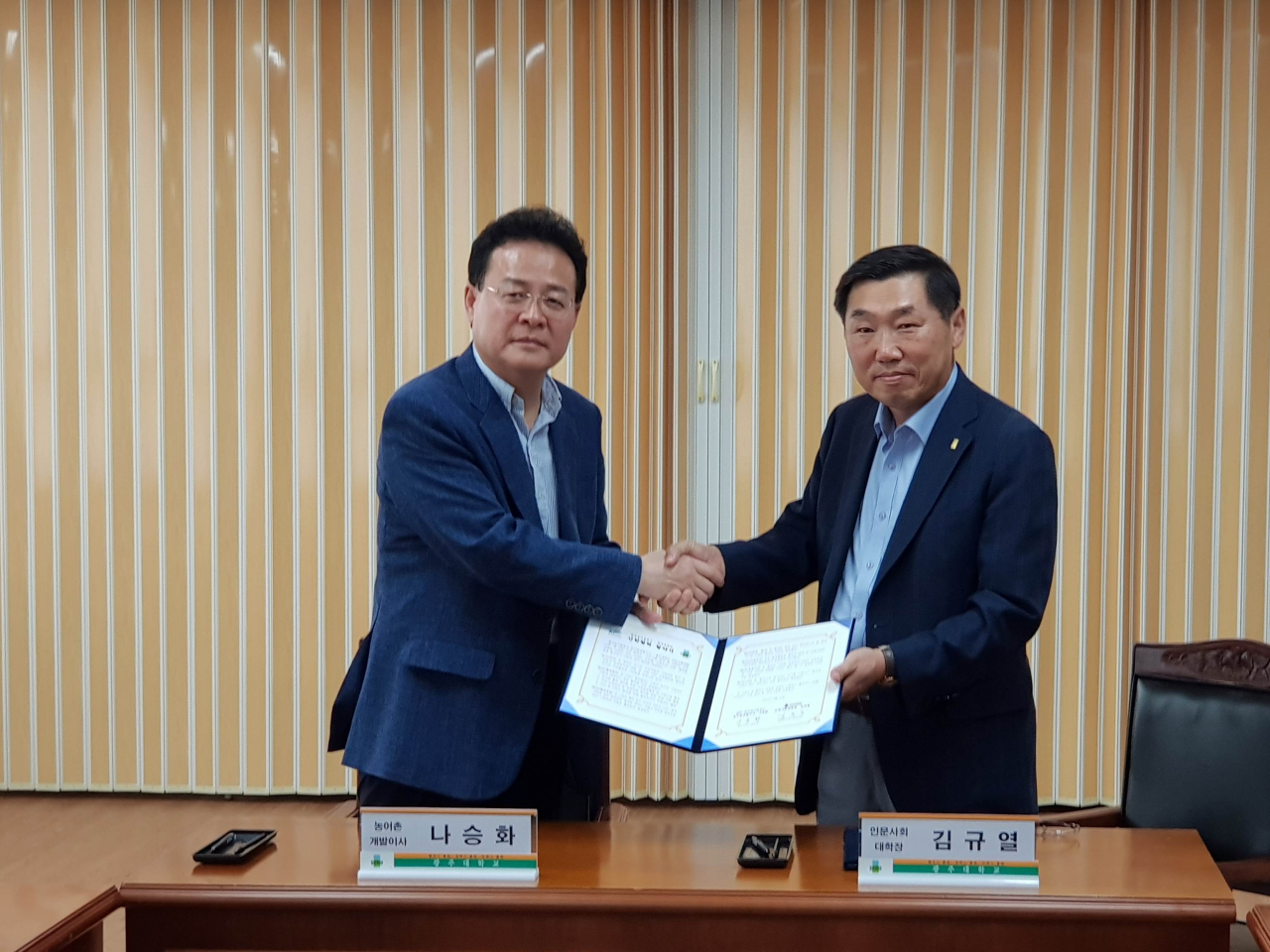 나승화 농어촌공사 농어촌개발이사(왼쪽)과 김규열 광주대 인문사회대학장이 업무협약을 체결한 뒤 포즈를 취하고 있다. [한국농어촌공사 제공]
