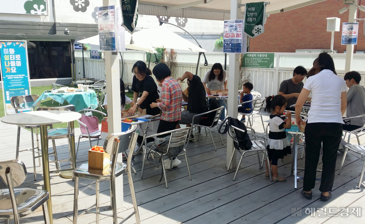 이화여대 정문 옆 골목 상점가인 이화52번가 일대에서 상권 활성화를 위한 사업들이 추진된다. 사진은 올해 6월 이화52번가 내 문화공간 이화쉼터에서 열린 ‘이화쉼터로 나들이 가요’ 프로그램 중 원목 가구 만들기 모습. [서대문구]