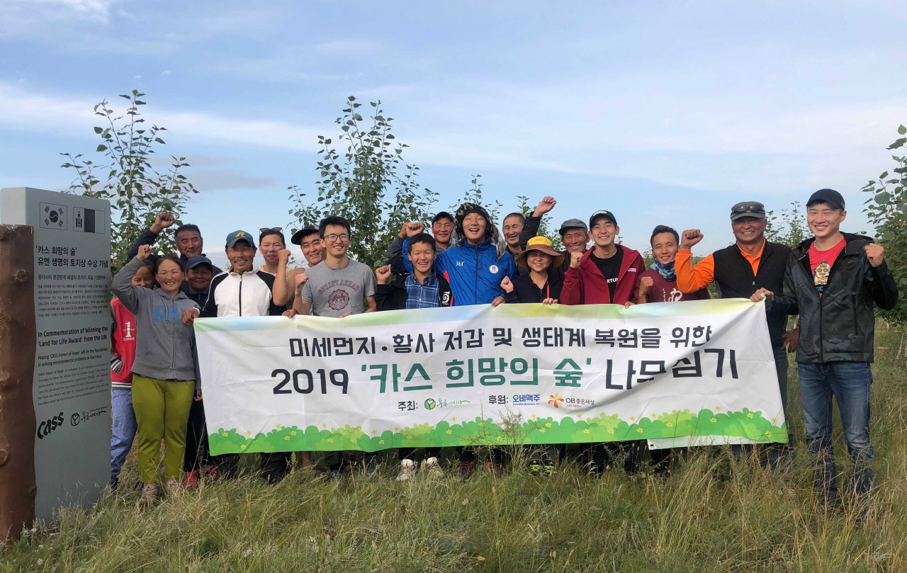푸른아시아 관계자, 몽골 대학생, 현지 주민으로 구성된 환경봉사단 20여명이 몽골 ‘카스 희망의 숲’ 일대에서 나무심기 봉사활동을 마치고 기념촬영을 하고 있다. [제공=오비맥주]