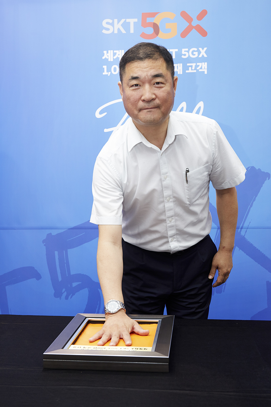 SK텔레콤은 세계 최초 5G 100만 명 돌파를 기념해 100만 번째 5G 고객을 찾아 22일 부산시 해운대구 T월드 대리점에서 축하 행사를 펼쳤다. 100만번째의 주인공인 이상국씨가 동판에 핸드프린팅을 하고 있다. [SKT 제공]