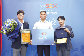 (사진 왼쪽부터) SK텔레콤 김성수 영업본부장, 100만번째 고객 이상국 씨, SK텔레콤 임봉호 부산마케팅본부장이 핸드 프린팅과 경품을 들고 포즈를 취하고 있다. [SKT 제공]
