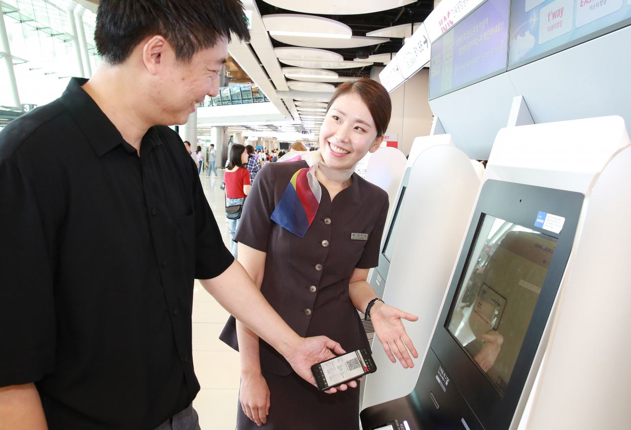 아시아나항공 공항 서비스 직원이 김포공항 국내선 터미널에서 셀프체크인 기기 사용법을 안내하고 있다. [아시아나항공 제공]
