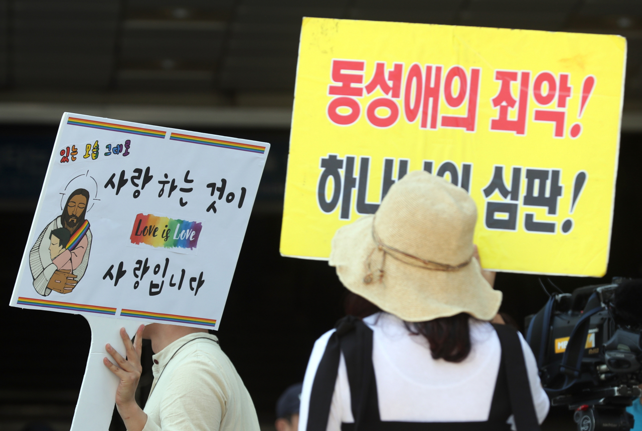 31일 오전 인천시 부평구 부평동 부평역 앞 쉼터광장에서 열린 '2019 제2회 인천퀴어문화축제'에서 한 축제 참가자와 종교단체 회원이 성 소수자에 대한 각자의 의견을 적은 푯말을 들고 있다. 연합뉴스