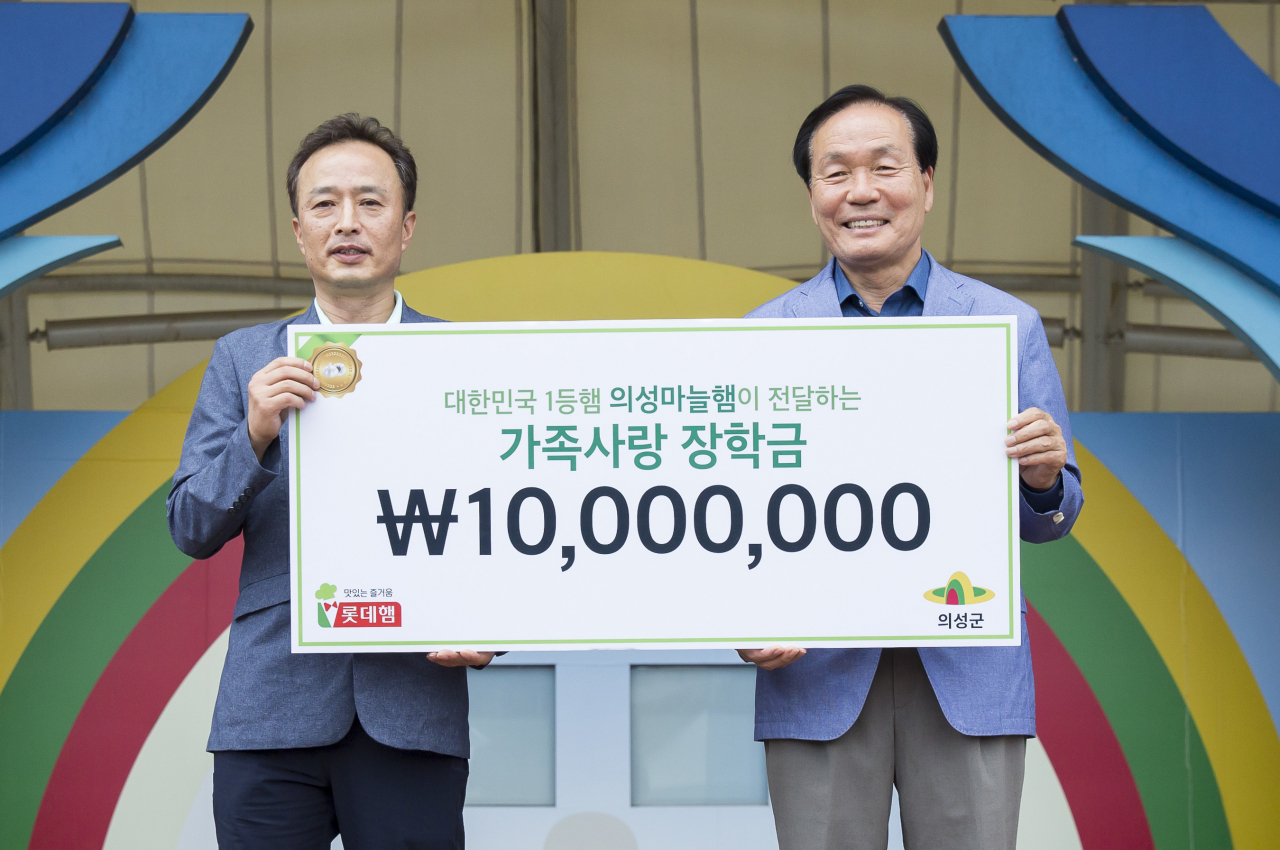 지난 6월 의성에서 진행된 10주년 의성마늘햄 가족캠프에서 이경석 롯데푸드 마케팅부문장(왼쪽)이 김주수 의성군수(오른쪽)에게 장학금을 전달하고 기념 사진을 찍고 있다. [롯데푸드 제공]