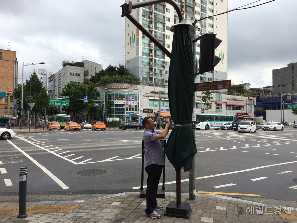 송파구청 직원이 태풍 링링이 북상함에 따라 보도에 설치된 그늘막을 접어 단단히 묶고 있다. [송파구]