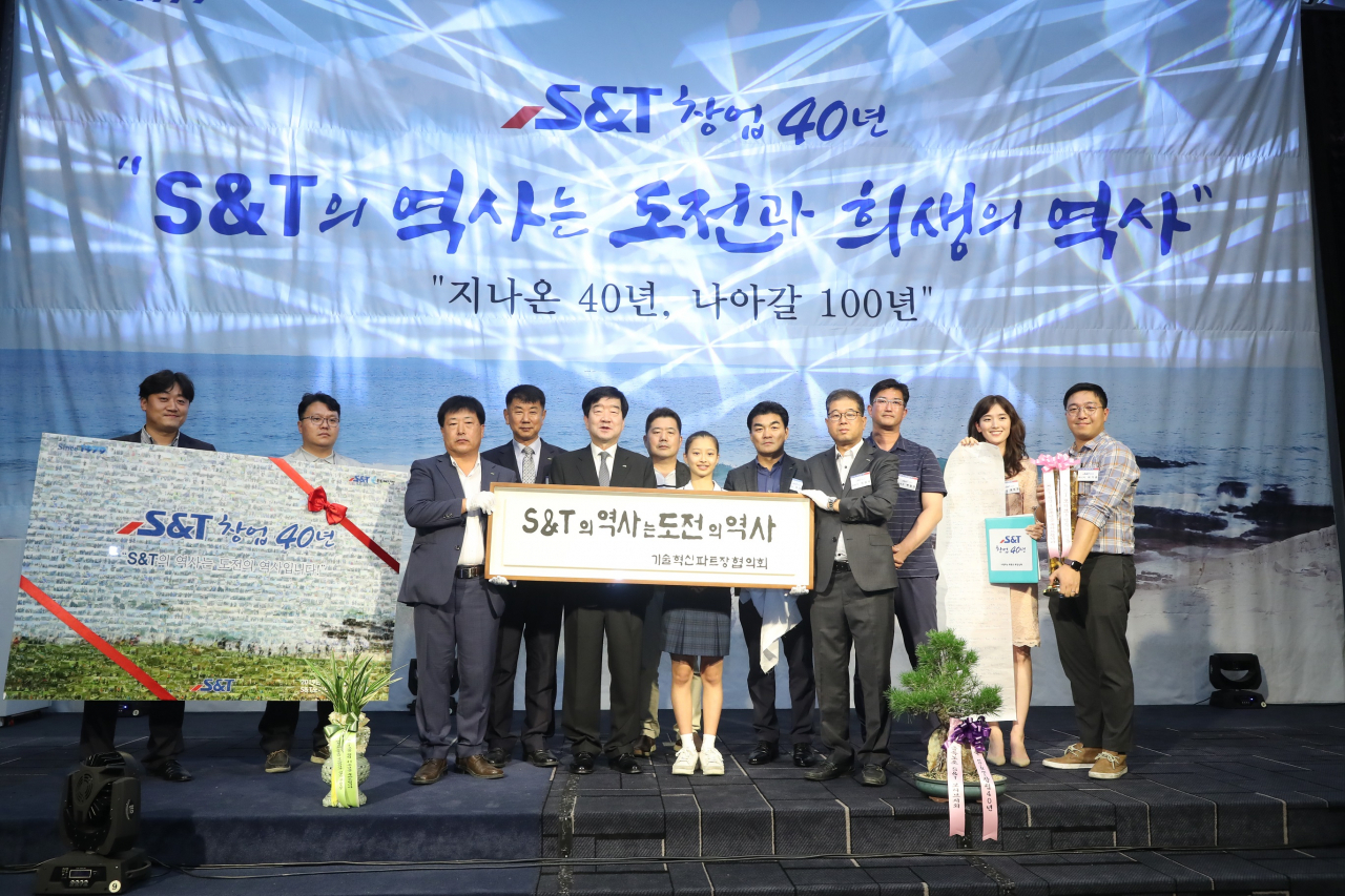 S&T 임직원들이 최평규 회장에게 40주년 기념선물 증정 후기념촬영을 하고 있다.