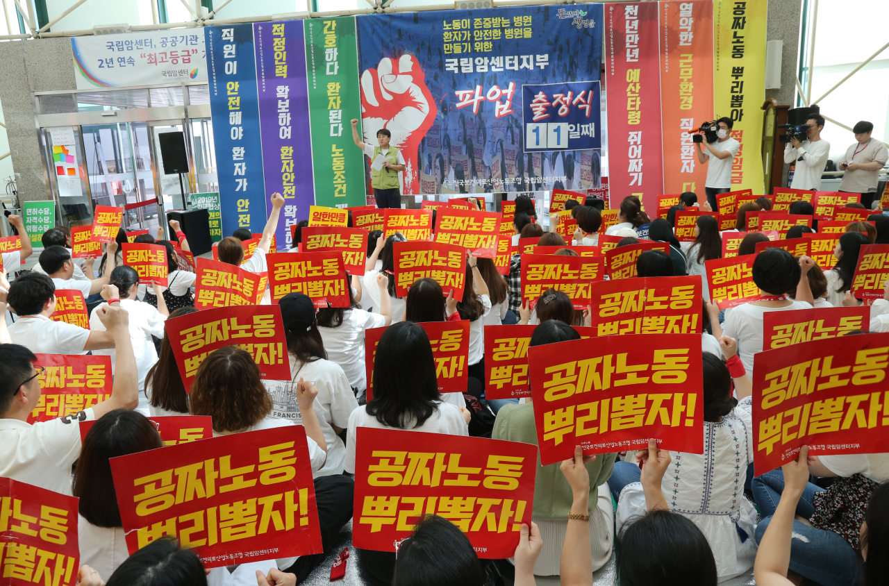 Health workers picket outside the National Cancer Center in Ilsan, north of Seoul, Monday, with signs reading, “Root out free labor!” (Yonhap)