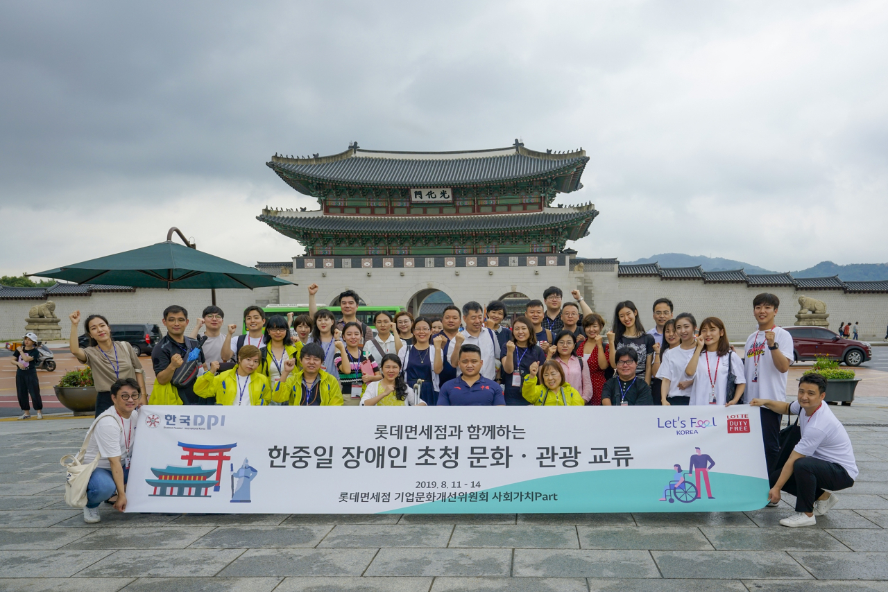 롯데면세점 기업문화개선위 사회가치파트 팀원들이 한·중·일 장애청년활동가 20여 명과 함께 한국의 현대·전통 문화를 체험한 후 서울 광화문 앞에서 기념촬영을 하고 있다. [사진제공=롯데면세점]