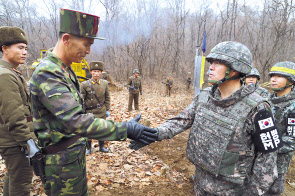 남북의 군인들이 DMZ 내 GP 철거 현장을 상호검증하기 위해 만나 악수하고 있다. [연합]