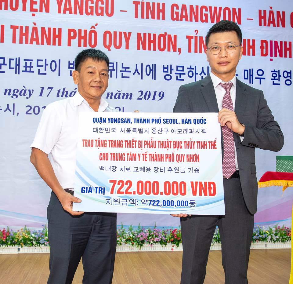 Head of Amorepacific Vietnam division Min Jeong-gi (right) delivers a medical device maintenance fee to head of Quy Nhon City Hospital Tran Ky Hau at a delivery ceremony on Wednesday. (Amorepacific)