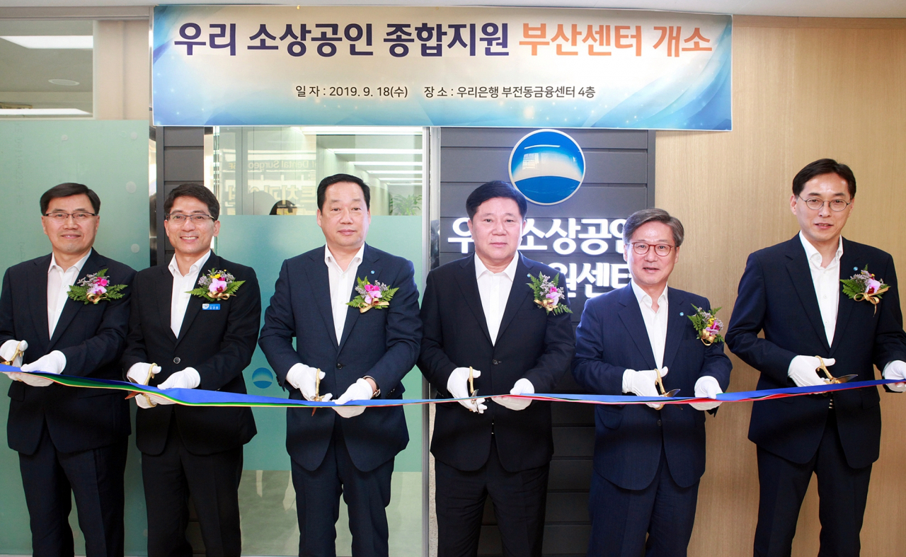 우리은행은 자영업자를 지원하기 위해 ‘우리 소상공인 종합지원센터’를 운영하고 있다. 하태중(왼쪽 네번째) 우리은행 중소기업그룹장 등 주요관계자가 지난 18일 부산센터 개소식에서 테이프 커팅을 하고 있다.[우리은행 제공]