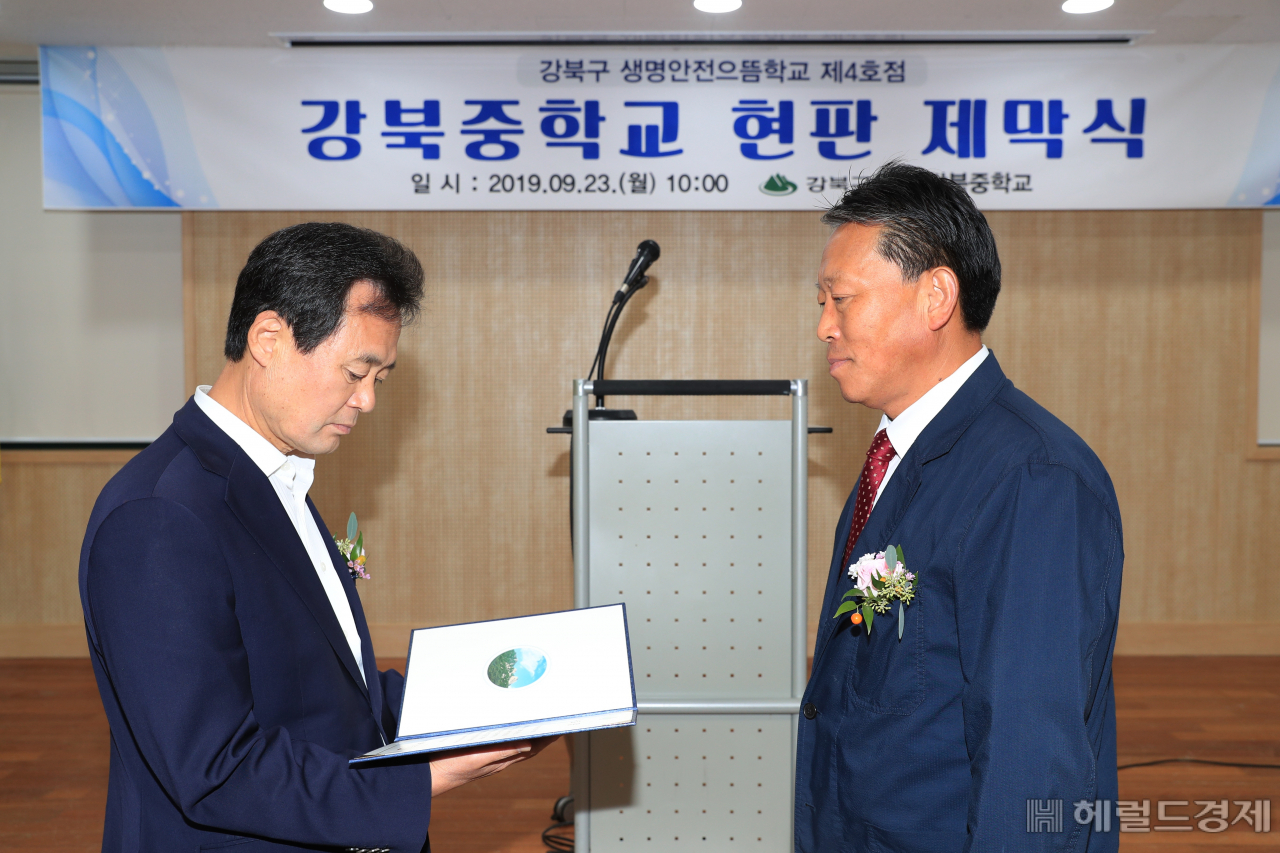 23일 생명안전으뜸학교 제4호점 제막식에 앞서 강북중학교 체육관 1층 소강당에서 박겸수 강북구청장(왼쪽)이 김정철 강북중학교장에게 교육 수료증을 전달하고 있다. [강북구 제공]